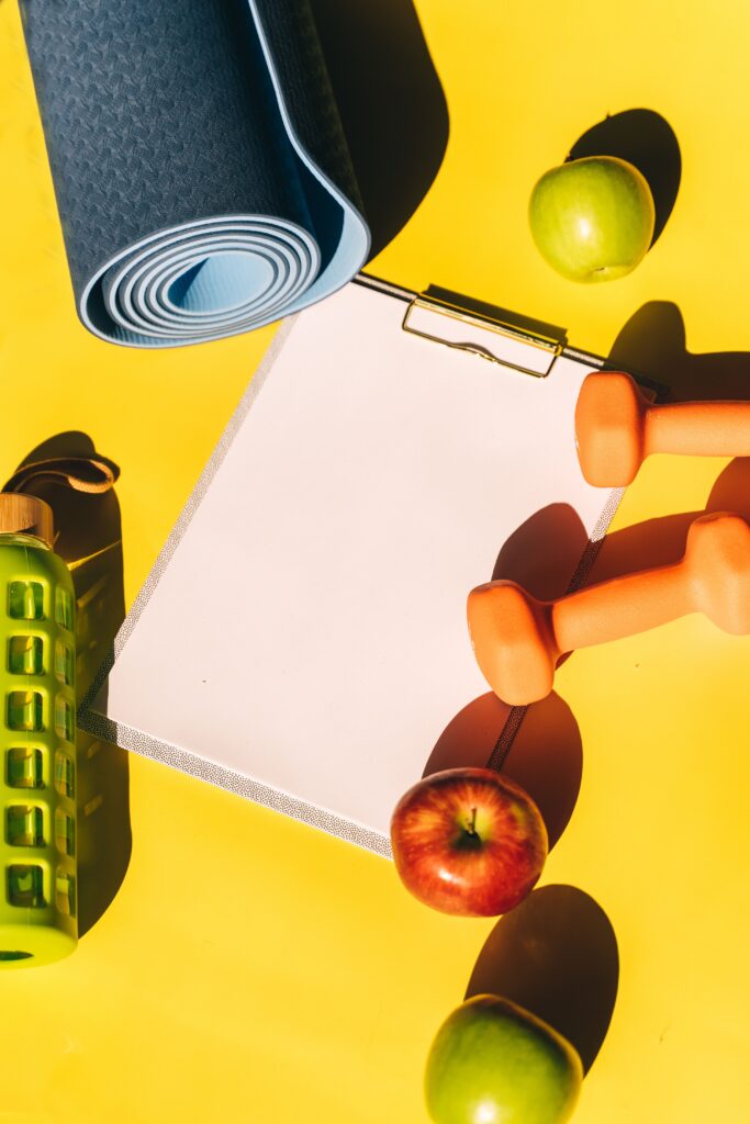 Implementos deportivos, frutas y una libreta de planificación que representan una rutina de ejercicio y alimentación saludable.