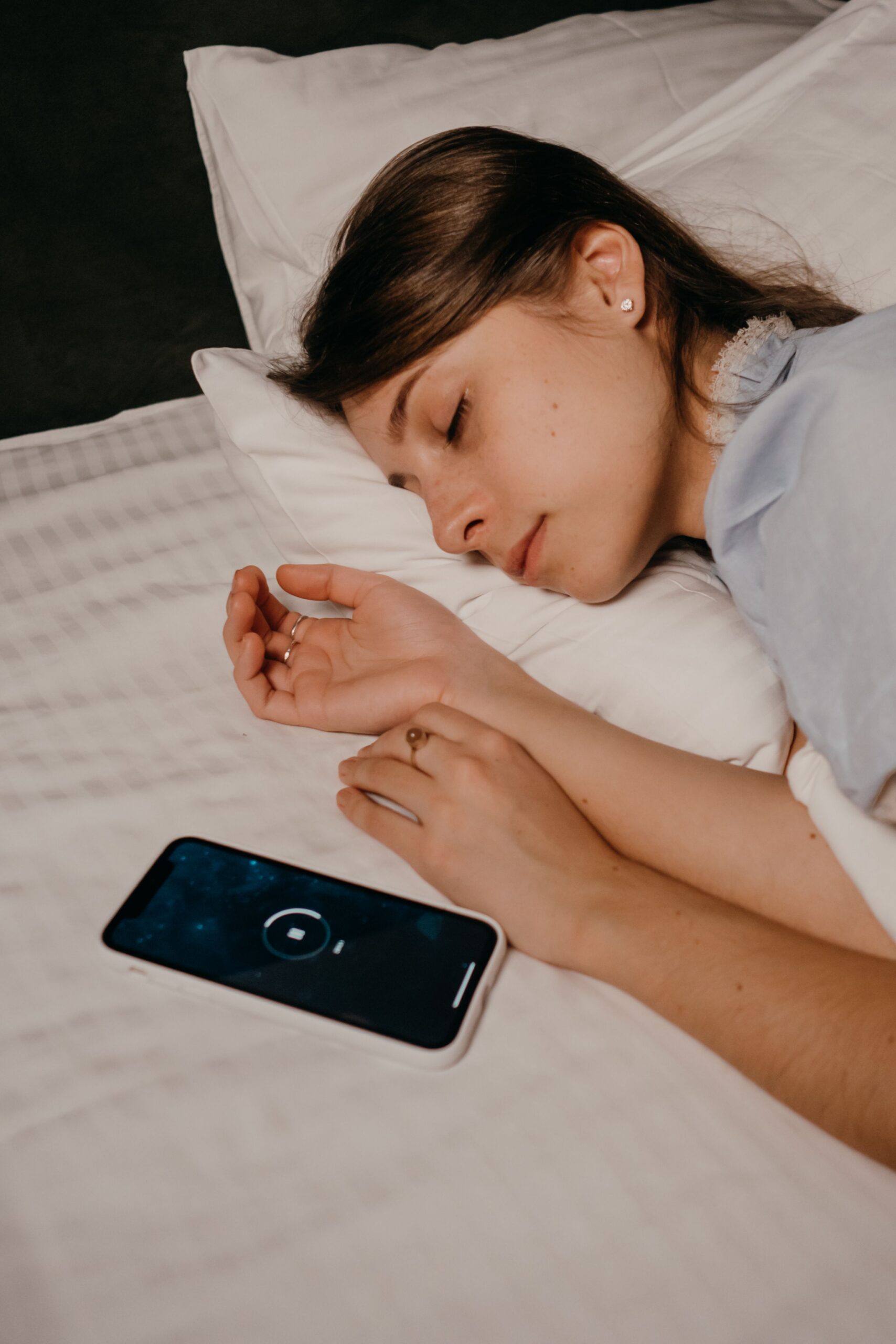 Mujer durmiendo junto a un teléfono móvil durante la noche mientras atraviesa las diferentes fases de los ciclos del sueño