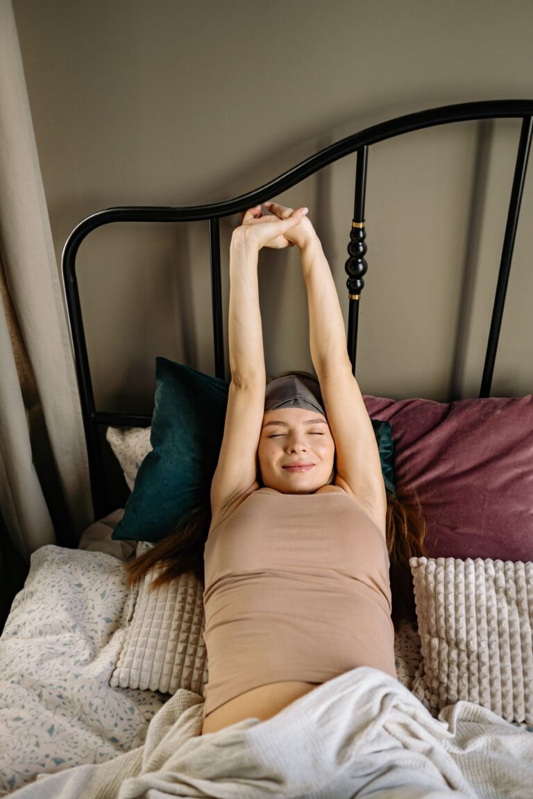 Mujer estirándose al despertar después de una noche de descanso y ciclos del sueño reparadores