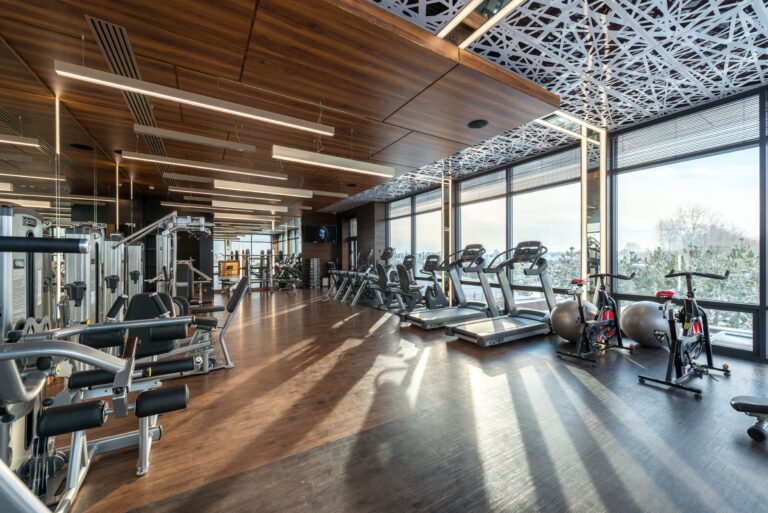 Gimnasio moderno con máquinas de ejercicio, caminadoras y bicicletas para realizar actividad física y mejorar la salud.