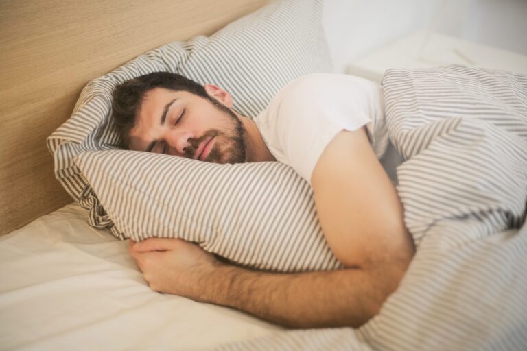 Hombre durmiendo cómodamente durante la fase de sueño profundo, esencial para la recuperación física y mental
