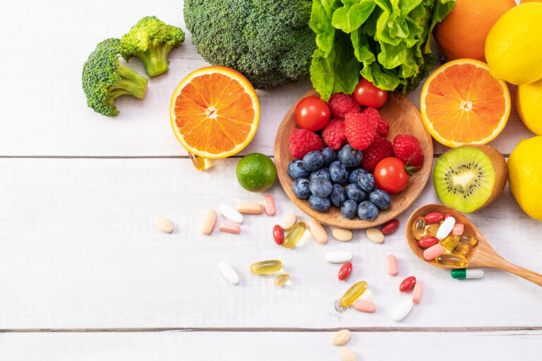 Diferentes frutas y verduras con sus respectivas tabletas de vitaminas.