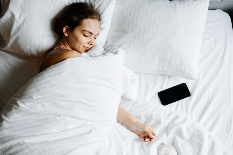 Mujer durmiendo plácidamente en una cama con el teléfono móvil apartado para favorecer un sueño profundo y reparador