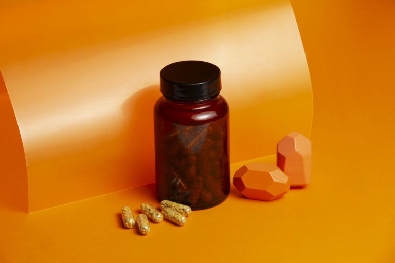 Vitamina C en cápsulas sobre un fondo naranja.