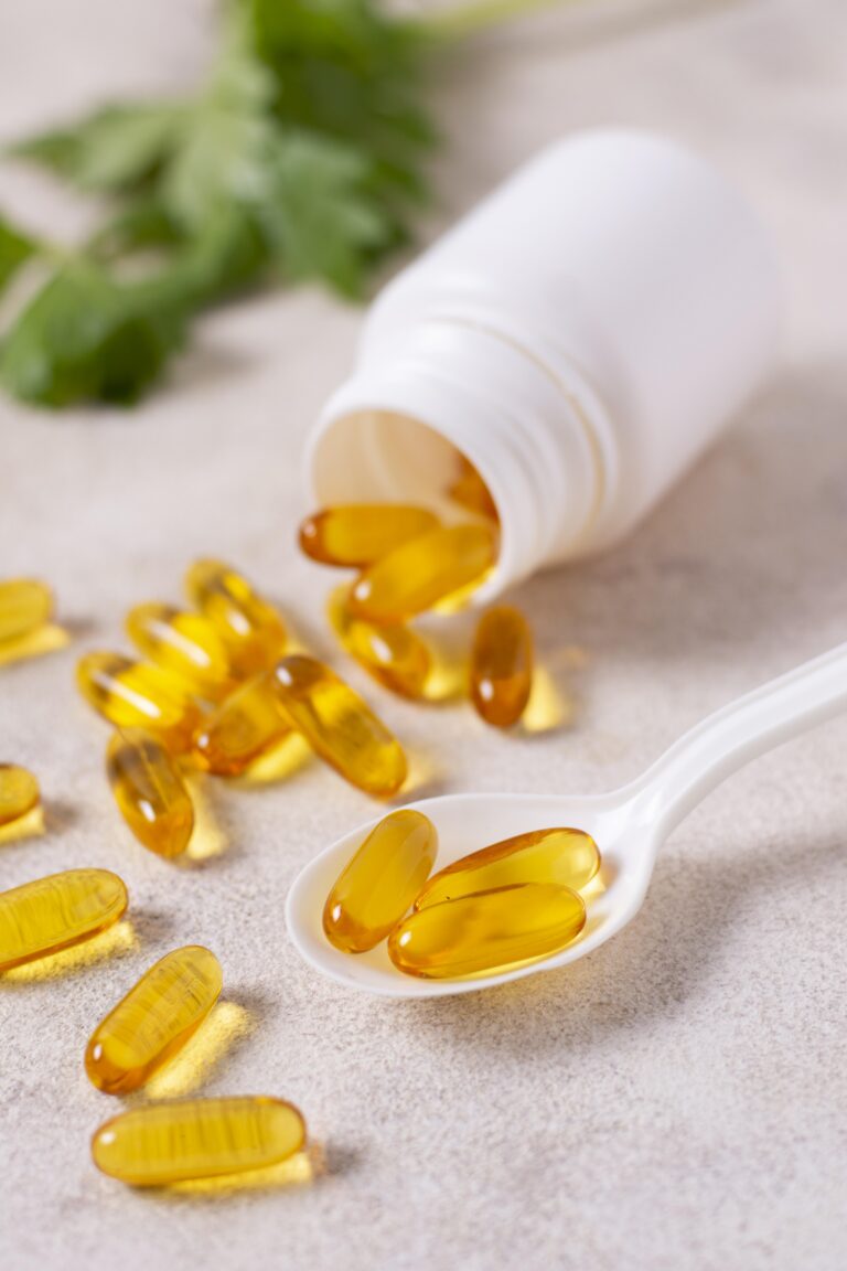 Vitaminas en una cuchara y regadas en una mesa.