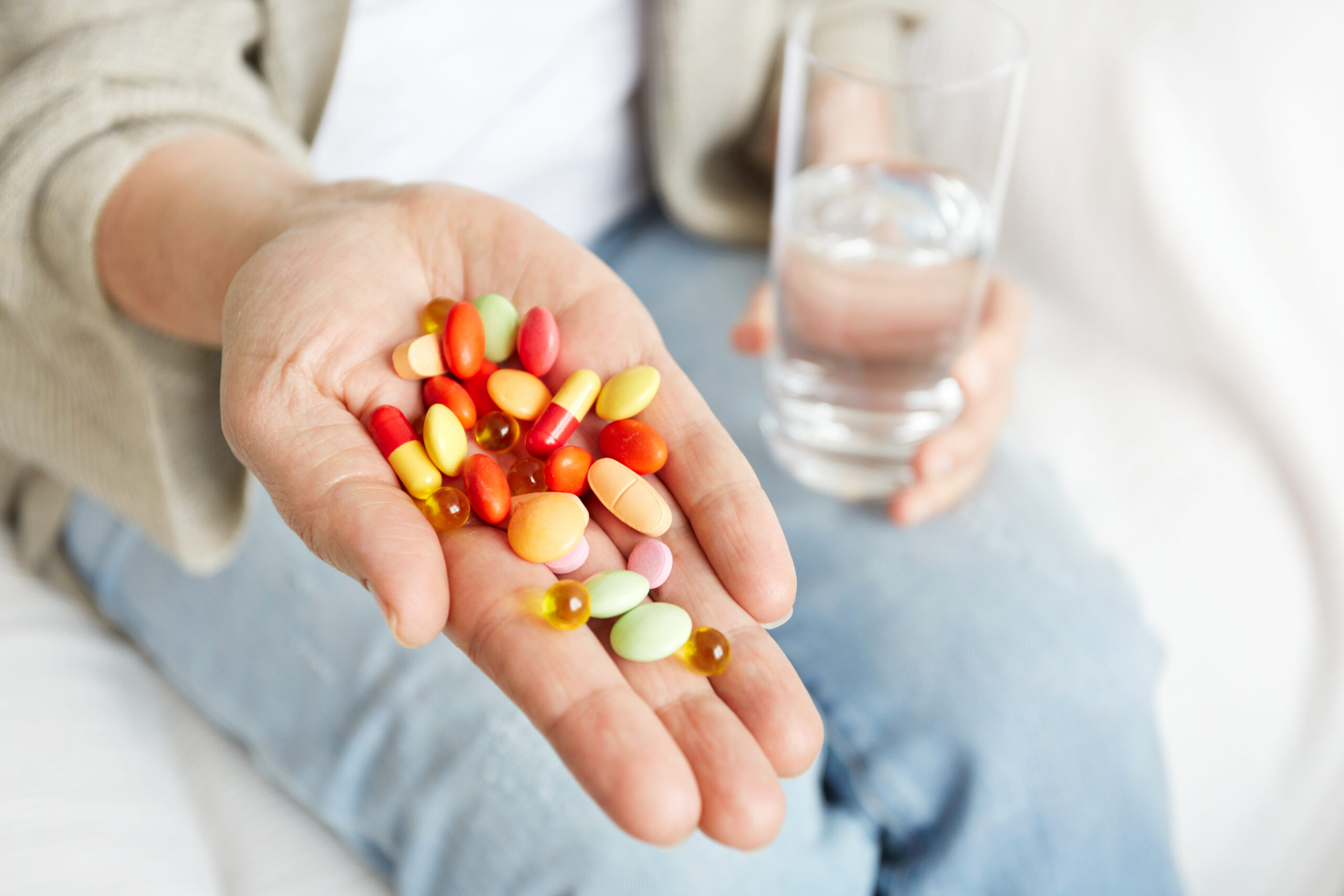Mujer sosteniendo diferentes tipos de vitaminas en tabletas.