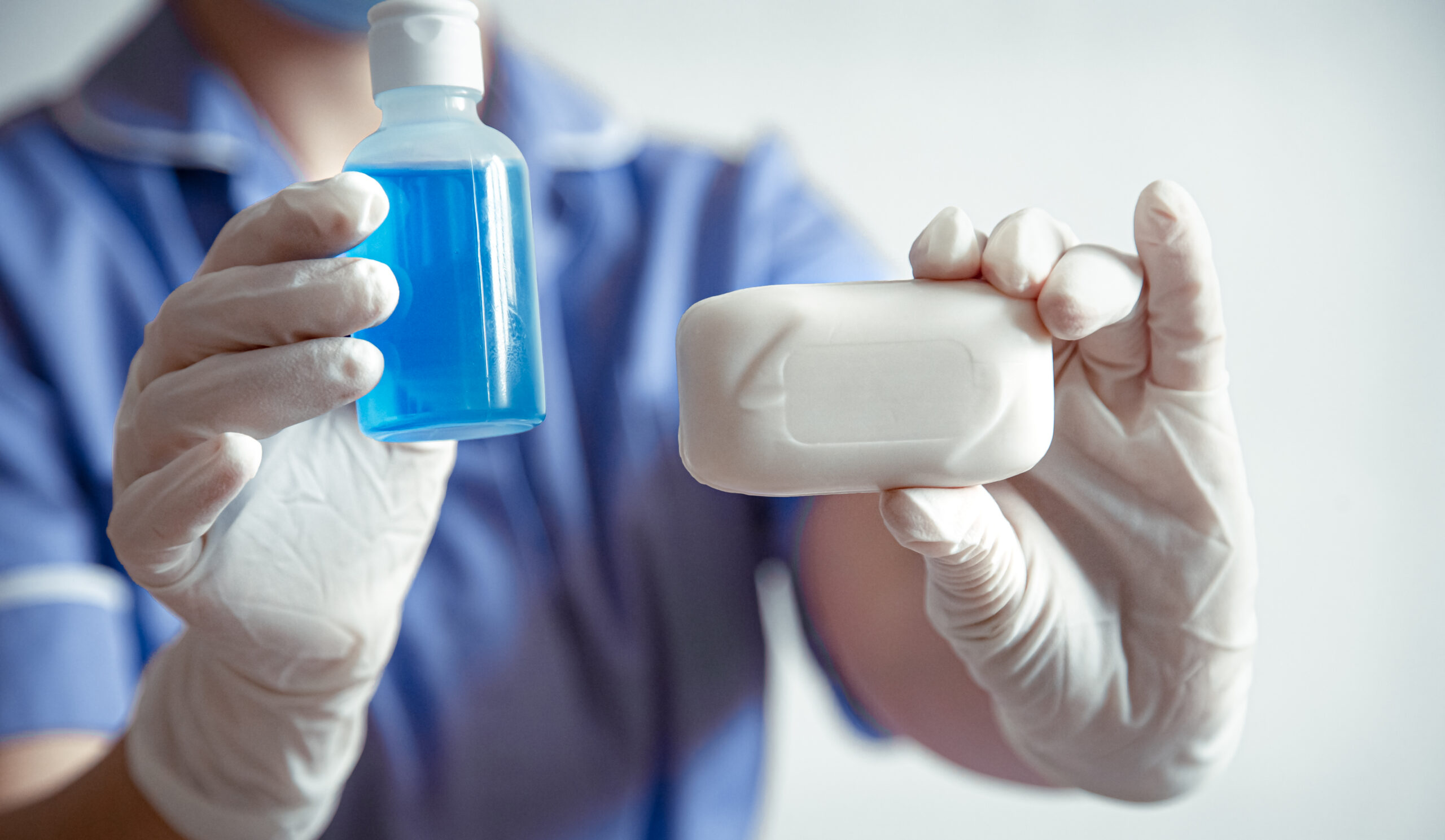 Persona sosteniendo un jabón y una botella de suero fisiológico.